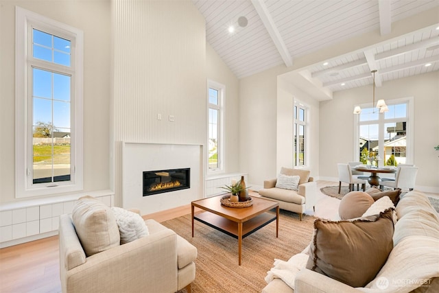 living area featuring beam ceiling, plenty of natural light, high vaulted ceiling, and light wood-type flooring