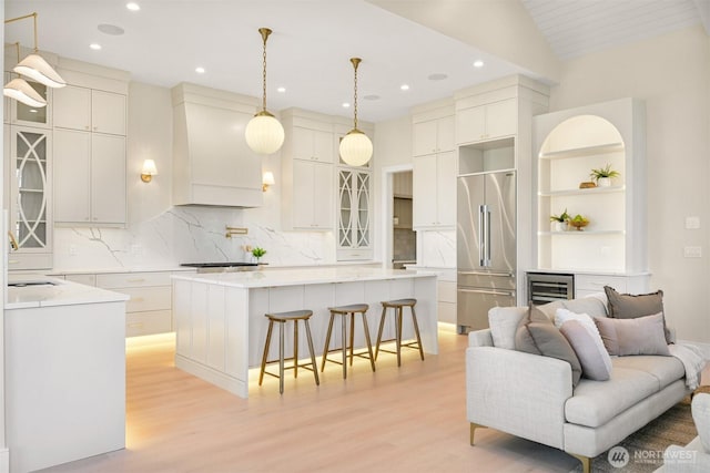 kitchen with a kitchen bar, a kitchen island, light wood-style flooring, and high end refrigerator