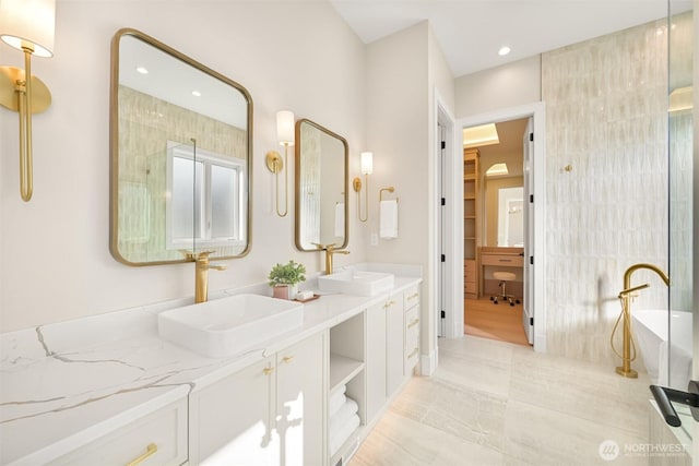 bathroom featuring double vanity, a soaking tub, recessed lighting, and a sink