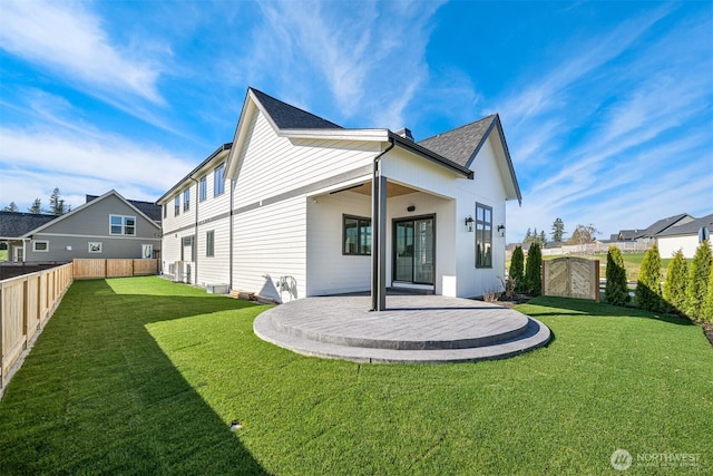 rear view of property with a patio area, a lawn, a shingled roof, and a fenced backyard