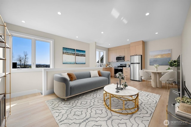 living room featuring recessed lighting, baseboards, and light wood finished floors