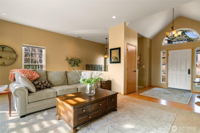 living area with lofted ceiling, light wood-style floors, and an inviting chandelier