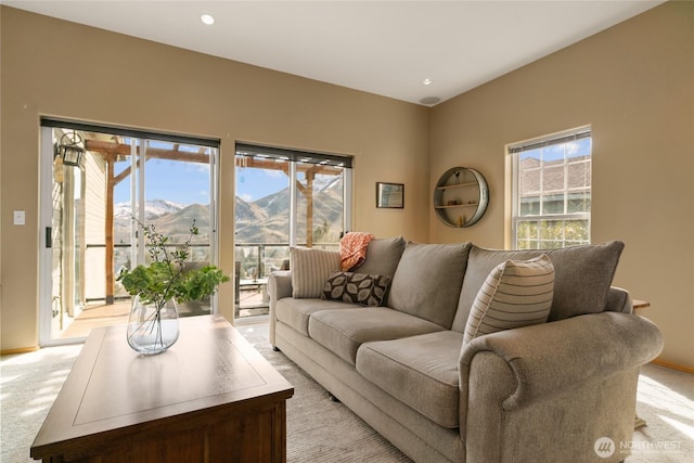 living area featuring light carpet, baseboards, a mountain view, and a wealth of natural light