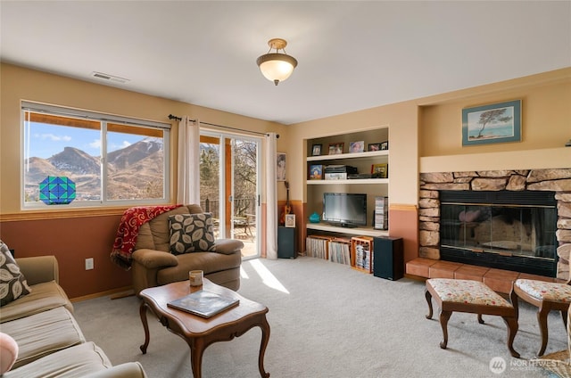 living area featuring carpet floors, visible vents, built in features, and a stone fireplace