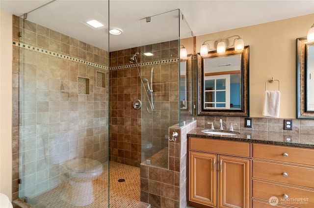 bathroom with backsplash, a tile shower, and vanity