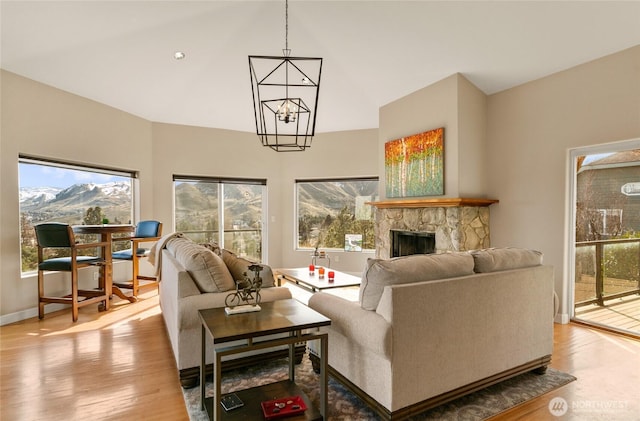 living area with a notable chandelier, a fireplace, light wood-style flooring, and a mountain view