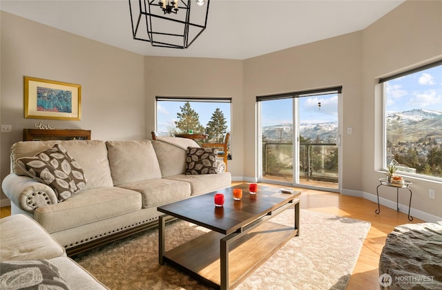 living room with light wood-type flooring, an inviting chandelier, and baseboards