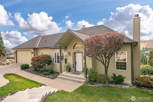 view of front facade with driveway, a shingled roof, a chimney, an attached garage, and a front yard