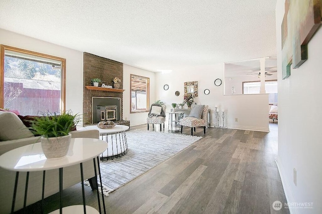 living area featuring ceiling fan, baseboards, a textured ceiling, and wood finished floors