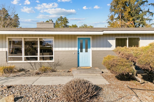 doorway to property featuring a chimney and brick siding