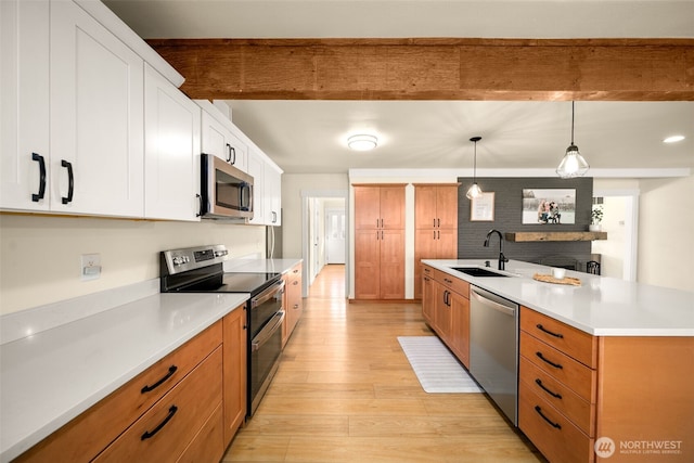 kitchen featuring stainless steel appliances, a sink, light wood-style flooring, and beamed ceiling