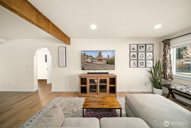 living room featuring arched walkways, beam ceiling, recessed lighting, and wood finished floors