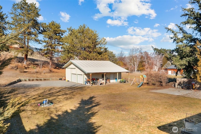 view of yard featuring a garage, an outbuilding, and a playground