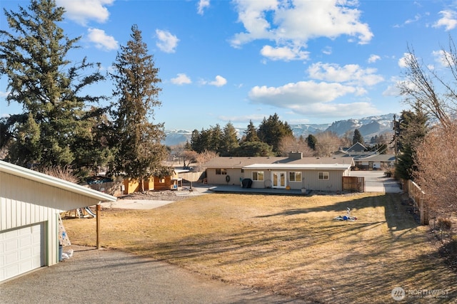 view of front of home featuring a garage, a front lawn, fence, and a mountain view