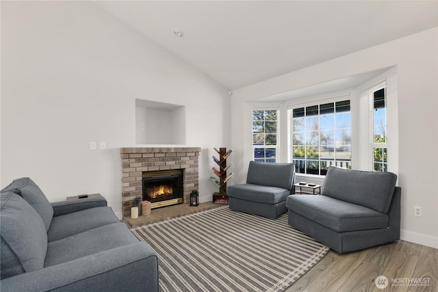 living room featuring a fireplace, baseboards, vaulted ceiling, and wood finished floors