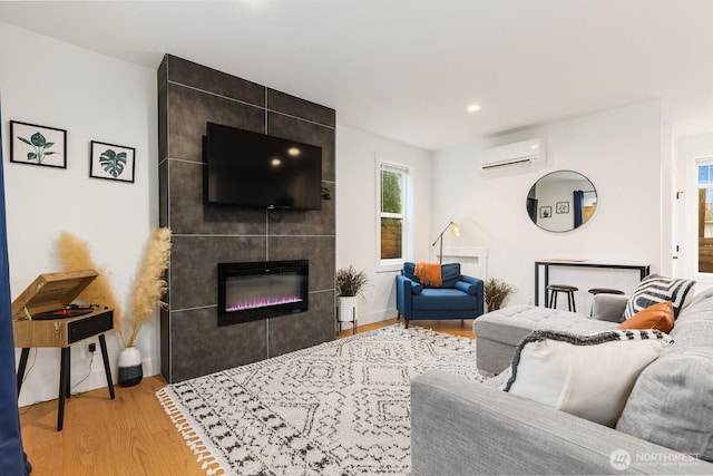 living area with a wall unit AC, a fireplace, baseboards, and wood finished floors