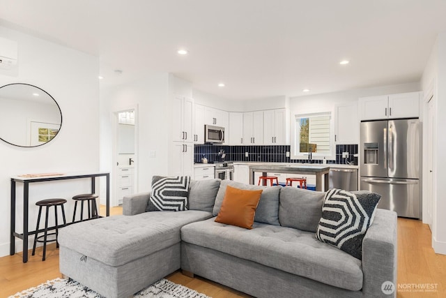 living room featuring an AC wall unit, light wood-type flooring, and recessed lighting