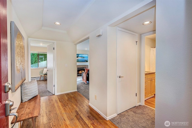 corridor featuring a baseboard heating unit, recessed lighting, baseboards, and wood finished floors