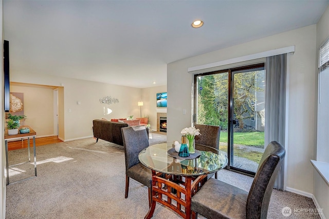 dining room featuring light carpet, recessed lighting, a fireplace, and baseboards