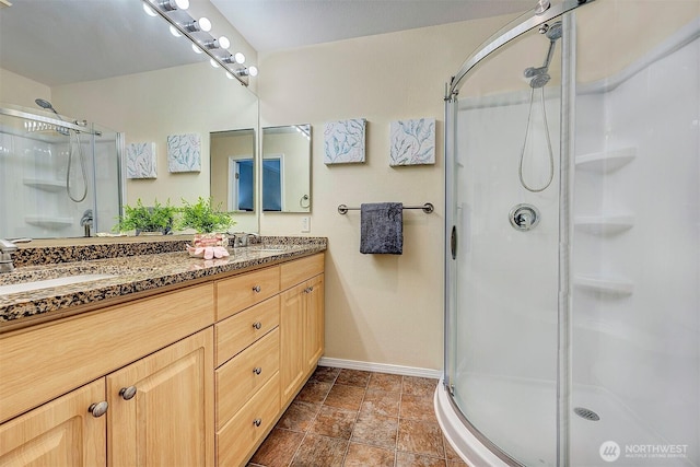 full bath with a sink, double vanity, and a shower stall