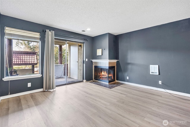 unfurnished living room with baseboards, a multi sided fireplace, and wood finished floors