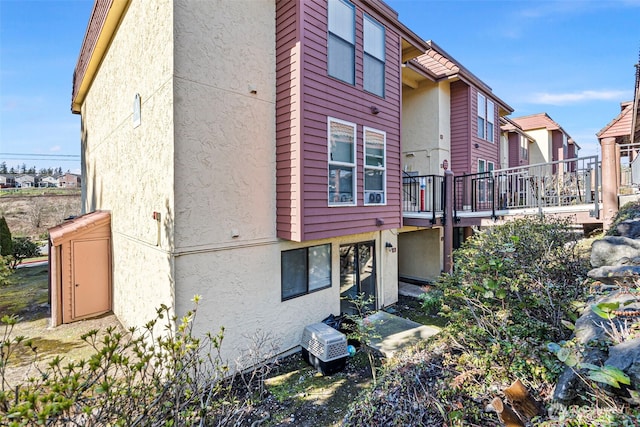 rear view of house featuring a wooden deck and stucco siding