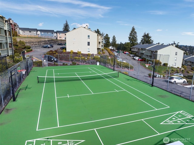 view of tennis court with a residential view and fence