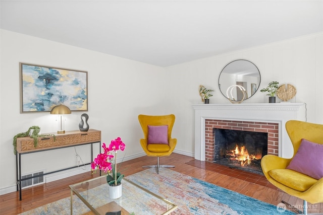 sitting room with baseboards, a fireplace, visible vents, and wood finished floors