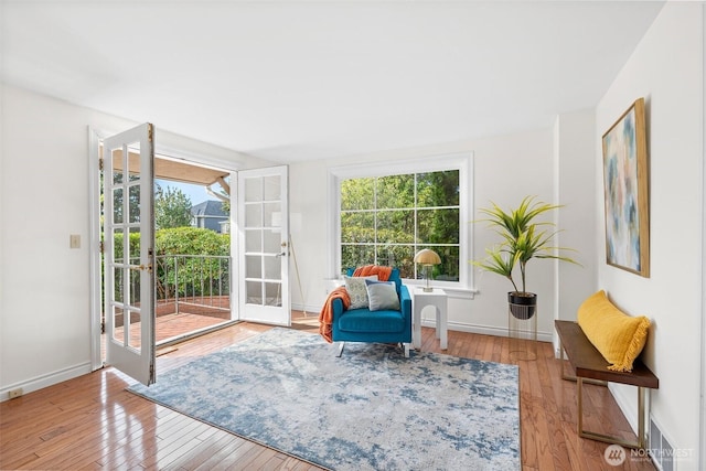 sitting room with plenty of natural light, visible vents, wood-type flooring, and baseboards