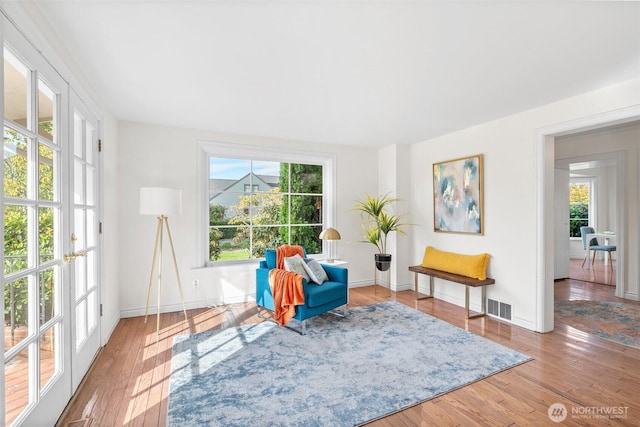 living area featuring hardwood / wood-style floors, visible vents, and baseboards