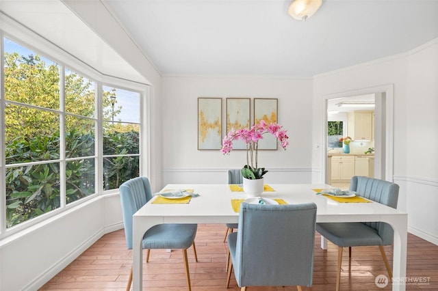 dining space featuring baseboards, wood finished floors, and crown molding