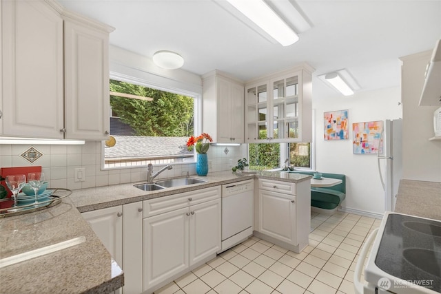 kitchen featuring tasteful backsplash, light countertops, white cabinetry, a sink, and white appliances