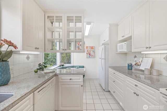 kitchen with white appliances, white cabinetry, and light tile patterned flooring