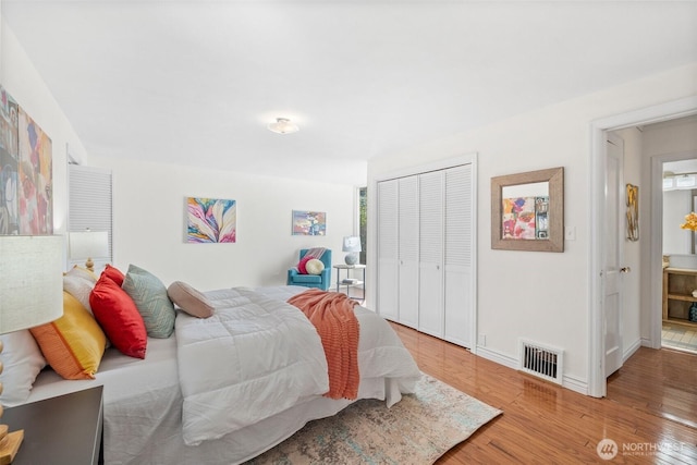 bedroom featuring a closet, wood finished floors, visible vents, and baseboards