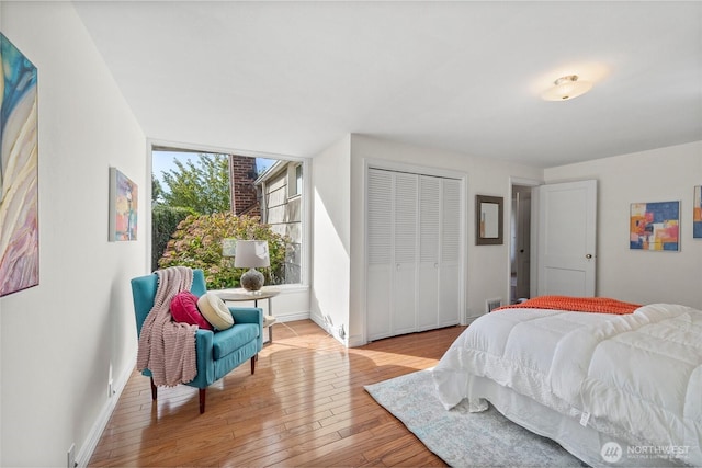 bedroom with light wood-style flooring, baseboards, and a closet