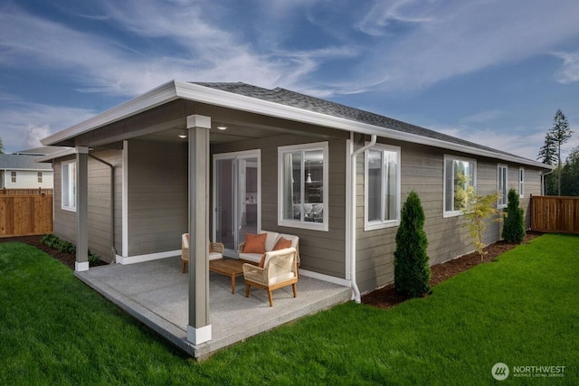 rear view of house featuring a patio area, a shingled roof, fence, and a lawn