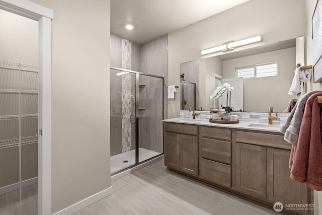 bathroom featuring a stall shower, a sink, and double vanity