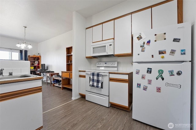 kitchen with white appliances, white cabinets, wood finished floors, a chandelier, and pendant lighting