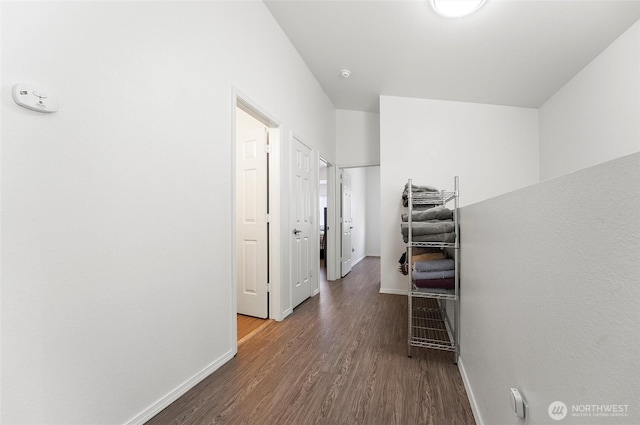 corridor with baseboards and wood finished floors