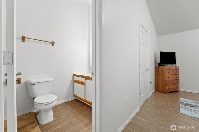 bathroom featuring baseboards, vanity, toilet, and wood finished floors