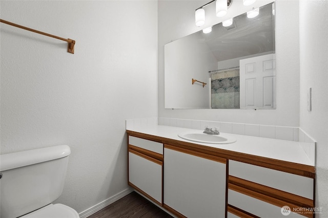 bathroom featuring toilet, wood finished floors, vanity, baseboards, and a shower with curtain