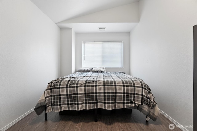 bedroom featuring visible vents, vaulted ceiling, baseboards, and wood finished floors