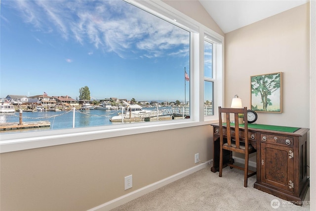 carpeted office space featuring lofted ceiling, a water view, and baseboards