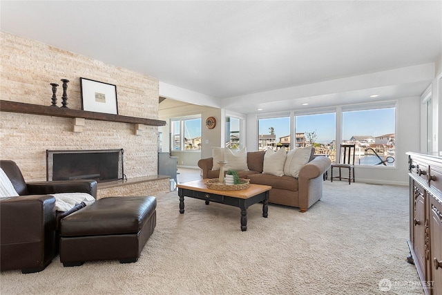 living area with recessed lighting, baseboards, light colored carpet, and a stone fireplace