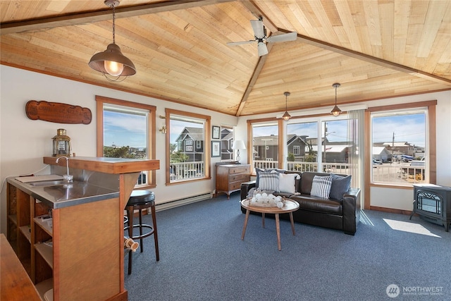 interior space with lofted ceiling, a baseboard heating unit, a sink, a wealth of natural light, and a wood stove