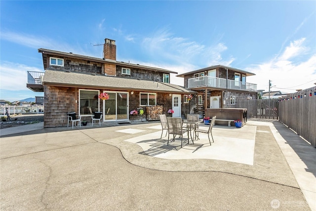 back of house with a balcony, a patio area, a hot tub, and fence