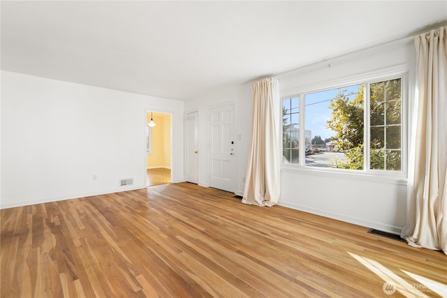 empty room with visible vents, baseboards, and light wood-style floors