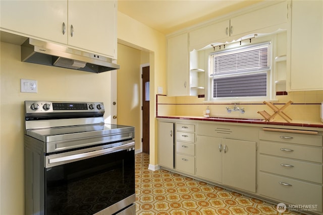 kitchen with electric range, under cabinet range hood, open shelves, tile countertops, and decorative backsplash