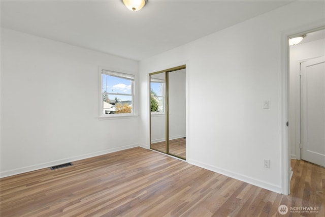 unfurnished bedroom with light wood-style flooring, visible vents, a closet, and baseboards