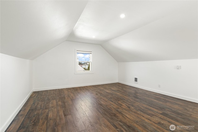 additional living space with dark wood-type flooring, visible vents, baseboards, and lofted ceiling